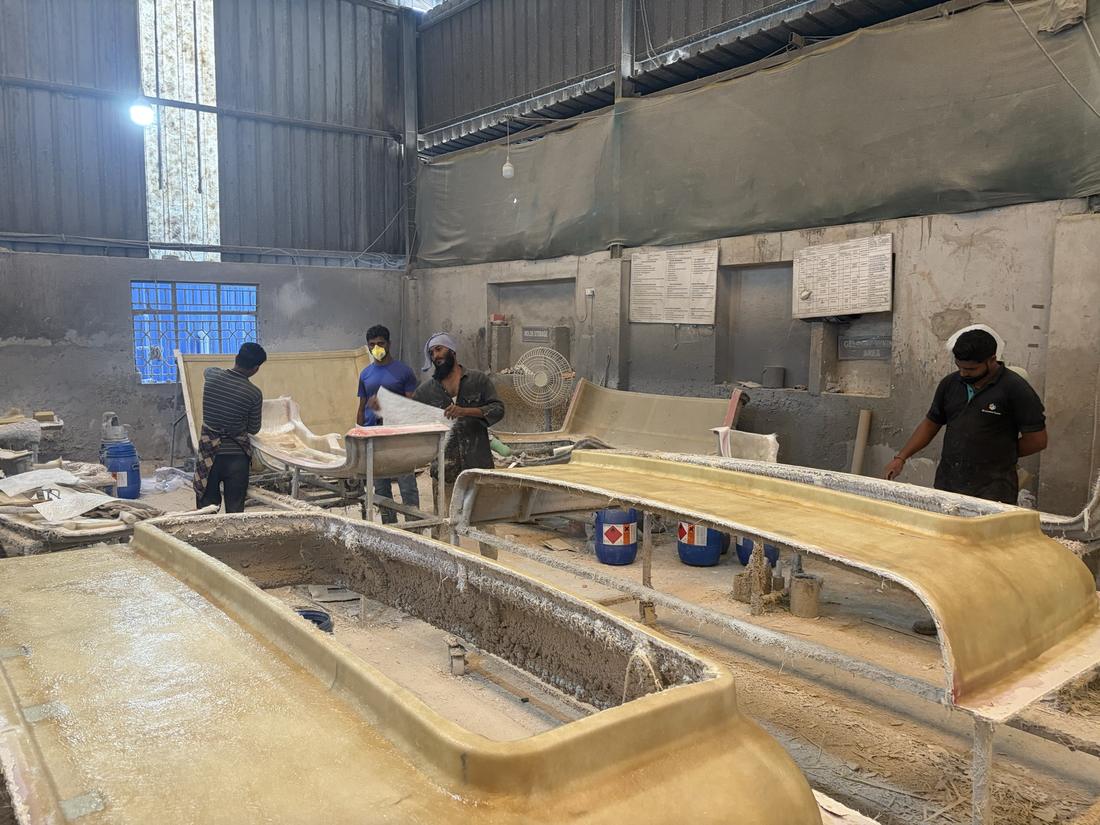 Workers laying up fibreglass parts on open moulds